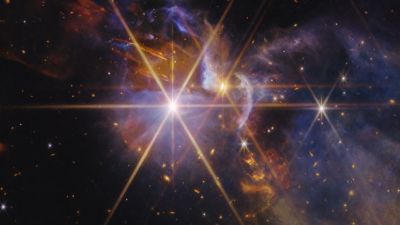 Webb NIRCam image of the FS Tau young star system in Taurus, showing protostellar jets and infrared outflows amid dusty nebulosity.