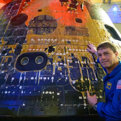 NASA astronaut Reid Wiseman, commander of the Artemis II mission points to the NASA logo and American flag on the...