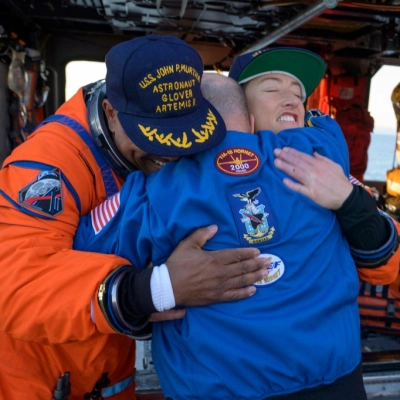 NASA astronaut Victor Glover, Artemis II pilot, left, and NASA astronaut Christina Koch, Artemis II mission specialist, right, hug Scott...