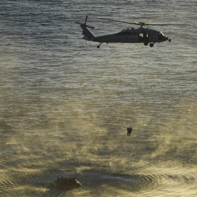 U.S. Navy divers and Artemis II astronauts aboard an inflatable raft are approached by helicopters and lifted away to the...