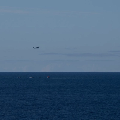 Tres MH-60 Seahawks de la Armada de los EE. UU. del Escuadrón de Helicópteros de Combate Marítimo (HSC) 23 sobrevuelan mientras pequeñas embarcaciones se acercan al Orion de la NASA...