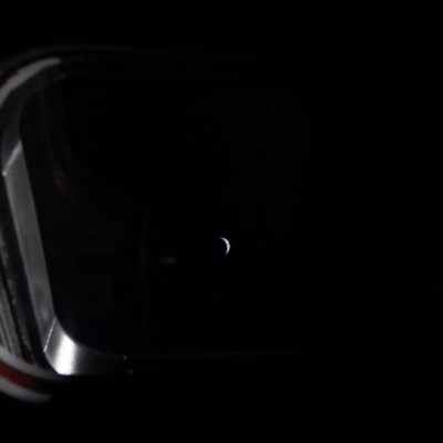 Peering out one of the four windows near the display console on the Orion spacecraft, the Earth is illuminated by...