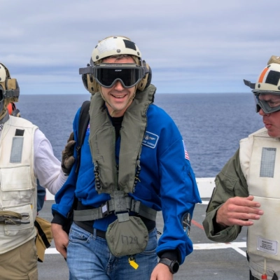 NASA Administrator Jared Isaacman, center, is greeted by Capt. Erik Kenny, commanding officer, USS John P. Murtha (LPD), right, after...