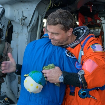 El astronauta de la NASA Reid Wiseman, comandante de Artemis II, le da un abrazo al cirujano de vuelo de la NASA Richard Scheuring junto a un MH-60 de la Armada...