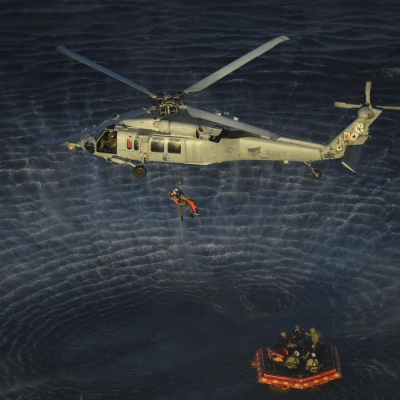 U.S. Navy divers and Artemis II astronauts aboard an inflatable raft are approached by helicopters and lifted away to the...