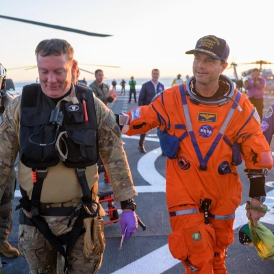 NASA astronaut Reid Wiseman, Artemis II commander is assisted off the flight deck after arriving aboard USS John P. Murtha...