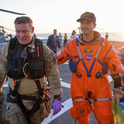 NASA astronaut Reid Wiseman, Artemis II commander is assisted off the flight deck after arriving aboard USS John P. Murtha...