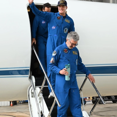 jsc2026e022271 (April 11, 2026) - Artemis II Mission Specialist Jeremy Hansen (center) returns home to Houston, stepping off a plane...
