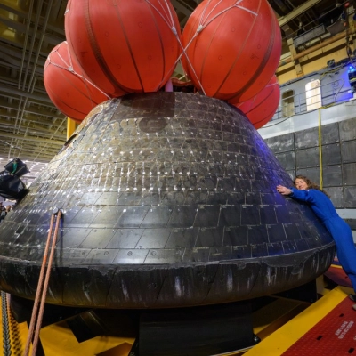 NASA astronaut Christina Koch, Artemis II mission specialist hugs the Orion spacecraft in the well deck of USS John P....