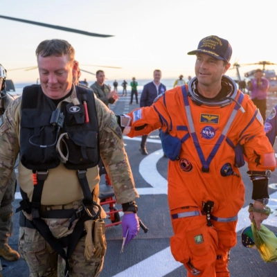 NASA astronaut Reid Wiseman, Artemis II commander is assisted off the flight deck after arriving aboard USS John P. Murtha...