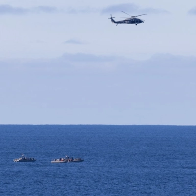 Un MH-60 Seahawks de la Armada de los EE. UU. del Escuadrón de Helicópteros de Combate Marítimo (HSC) 23 sobrevuela mientras pequeñas embarcaciones se acercan al Orion de la NASA...