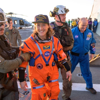 NASA astronaut Christina Koch, Artemis II mission specialist is assisted off the flight deck after arriving aboard USS John P....