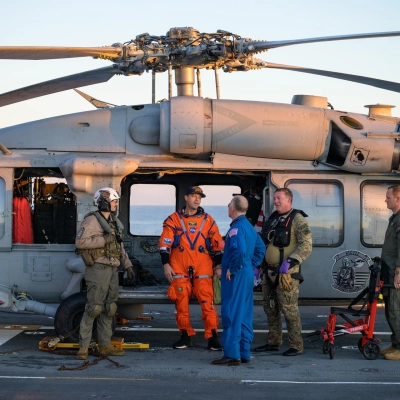 NASA astronaut Reid Wiseman, Artemis II commander is seen standing next to a Navy MH-60 Seahawk from Helicopter Sea Combat...